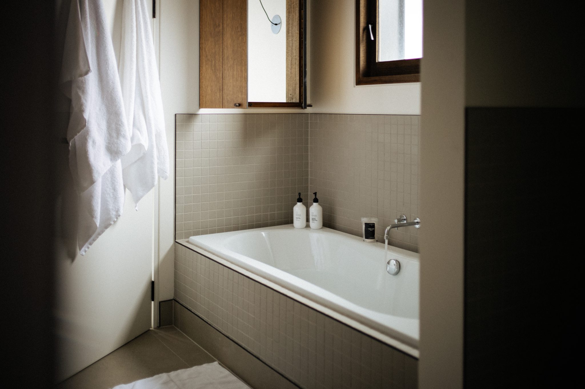 Bathtub in the Luna Residence, a fluffy white robe hangs on the door